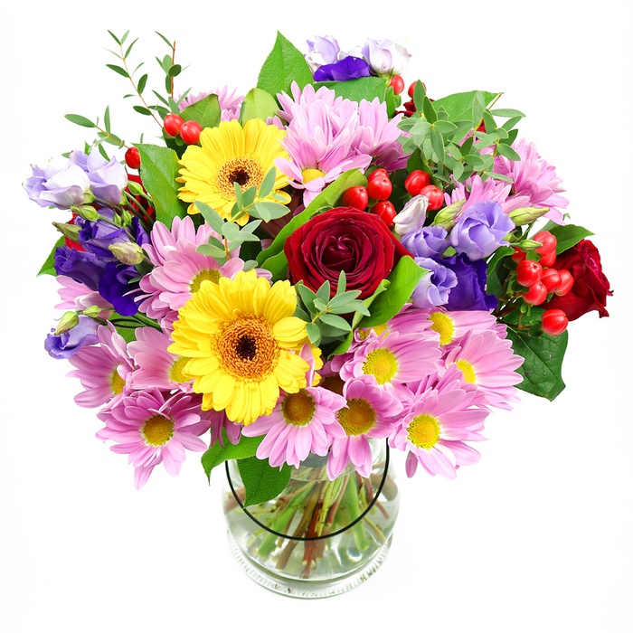 A lush, rounded bouquet stands proudly in a simple clear glass vase, photographed against a clean white background that makes the colours appear even more vivid. At its heart, deep red roses spiral open in velvety layers, lending a sense of classic passion and sincerity. Nestled nearby, bright yellow gerbera daisies with rich brown-orange centres shine with joyful warmth, like cheerful faces turned toward the sun. Surrounding these focal blooms, generous sprays of soft pink and pale lilac daisies or chrysanthemums create a cushion of delicately fringed petals, each tiny yellow centre adding a subtle point of light. Interlaced among them, slender stems of purple and lavender lisianthus introduce cooler tones; their gently fluted, bell-like flowers ripple softly around the arrangement and give it an elegant, slightly whimsical feel. Here and there, clusters of small, round red hypericum berries emerge like polished beads, providing uplifting bursts of colour and contrasting texture. A mix of glossy dark leaves and finer, lighter green foliage fans out from the base, giving the bouquet a fresh, abundant look, similar to flowers gathered from a well-loved garden near Kingston's leafy Richmond Road. Through the transparent vase you can see the stems carefully cut to even lengths and resting in clear water, a detail that reveals the florist's attention to structure and longevity. The image conveys an atmosphere of happy celebration and heartfelt thoughtfulness, ideal for a birthday delivery in Kingston, a thank-you for neighbours near the river, or a bright centrepiece on a family table. Every element feels balanced and intentional, combining romance, cheerfulness, and natural charm in one radiant display.