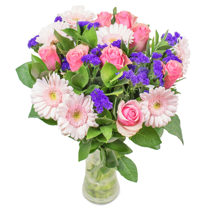 An elegant, locally crafted floral bouquet sits poised in a clear glass vase, ready for same-day delivery across Kingston. Arranged by a seasoned florist with intimate knowledge of local preferences, the bouquet showcases the perfect union of 7 to 9 pink roses-some with petals just beginning to unfurl, others retaining the iconic spiral of a freshly cut bloom-paired with 5 to 7 pale pink Gerbera daisies. These large-headed gerberas, a favourite in Kingston's high-street shops, provide visual brightness, their soft, nearly white centres adding a delicate transition to the gently curling petals. Threaded among these, vivid purple filler flowers, reminiscent of statice or limonium, inject depth and vibrancy, their crisp texture contrasting beautifully with the plushness of the roses and gerberas. Around the base, lush green foliage fosters a scene of abundance and freshness, as if gathered on a morning walk through Canbury Gardens or along the Thames embankment. The transparent vase reveals the stems neatly aligned in clear water, emphasising the bouquet's natural origins and expert handcraft. A thoughtful gift for birthdays, anniversaries, or as a cheerful accent in a Kingston office or home, this arrangement radiates celebration, sincerity, and a sense of the local landscape-ensuring every recipient feels honoured and uplifted by its presence.